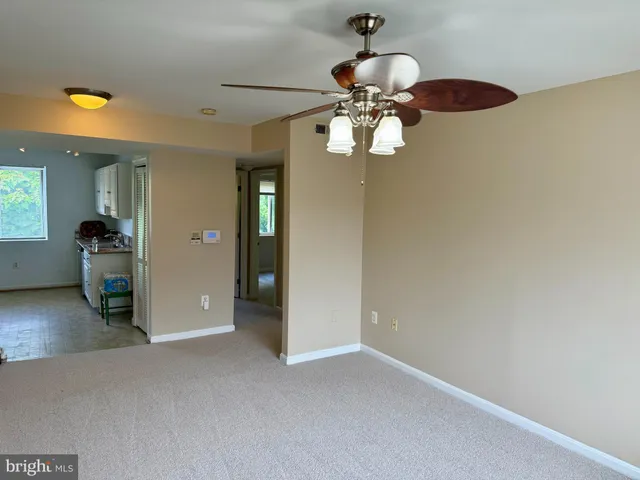 an empty room with a chandelier fan and wooden floor