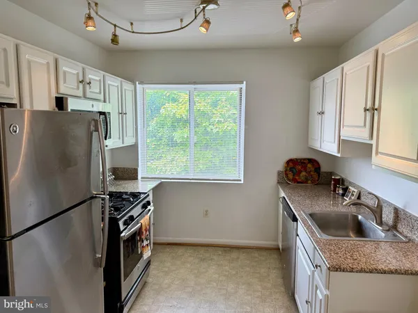 a kitchen with stainless steel appliances granite countertop a refrigerator a sink a stove and a refrigerator