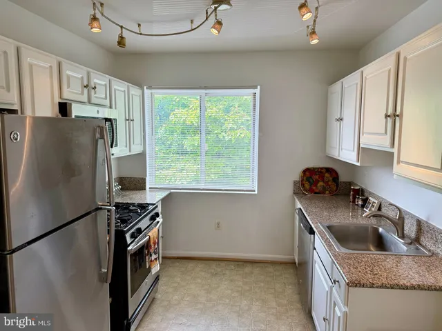 a kitchen with stainless steel appliances granite countertop a refrigerator a sink a stove and a refrigerator