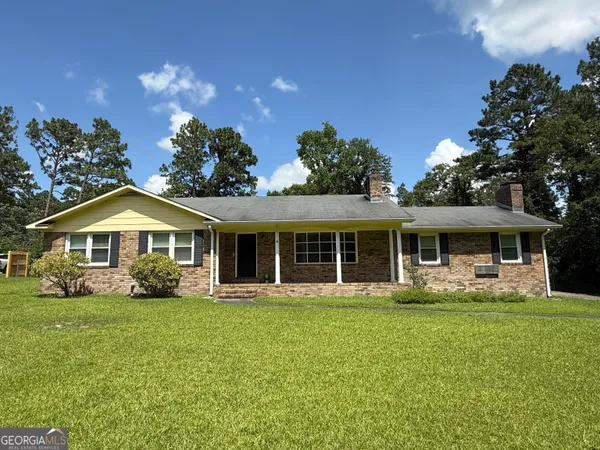 a front view of a house with a garden and trees