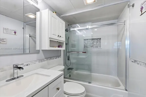 a bathroom with a granite countertop bathtub shower sink vanity and toilet