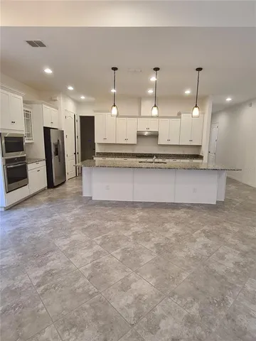 a large kitchen with kitchen island a sink stainless steel appliances and a counter top space