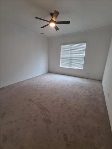 a view of an empty room with a ceiling fan and window