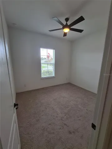 an empty room with windows and fan