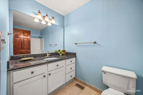 a bathroom with a granite countertop toilet sink and mirror