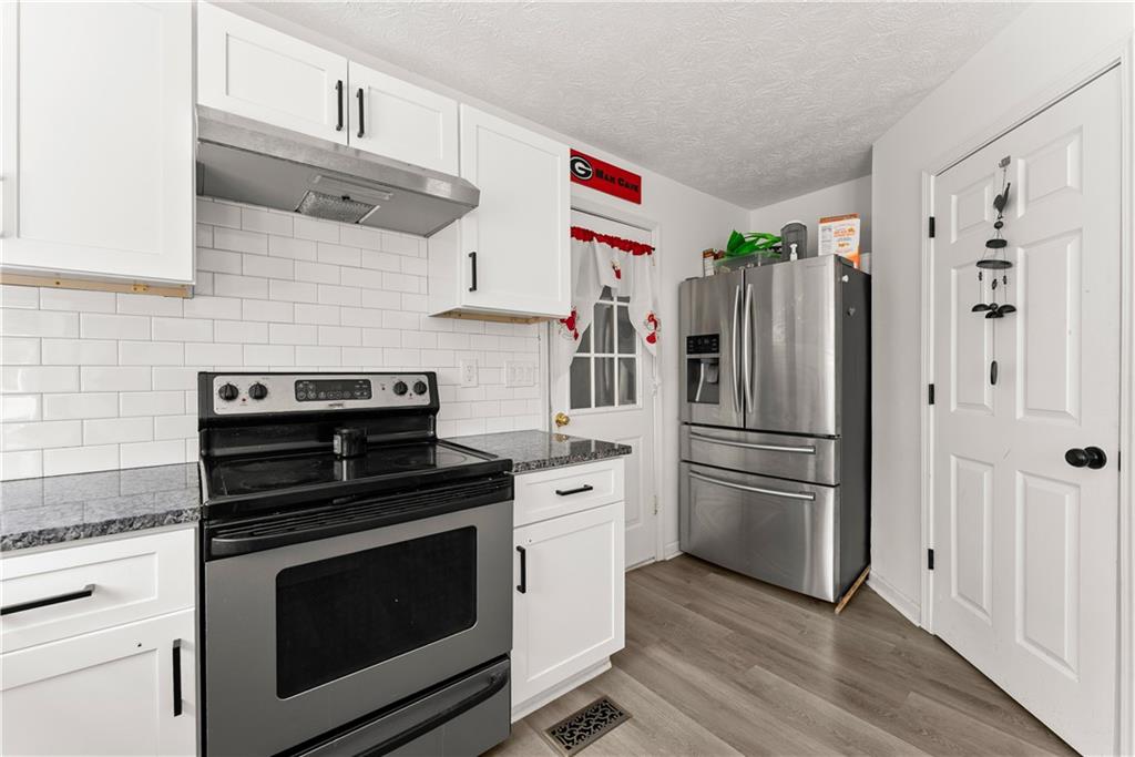 322 Wyngate Road Auburn, GA 30011 - Photo 19 of 44 a kitchen with cabinets stainless steel appliances and wooden floor