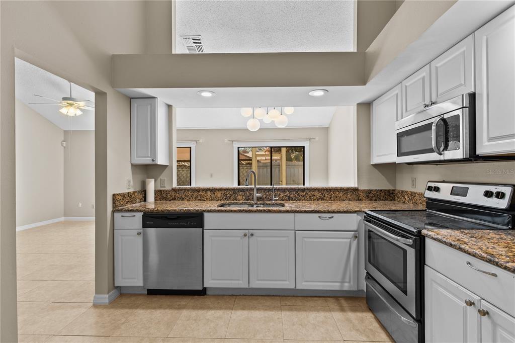 111 Feather Edge Loop, Unit 4B Lake Mary, FL 32746 - Photo 4 of 27 a kitchen with stainless steel appliances granite countertop a stove top oven a sink dishwasher and a refrigerator
