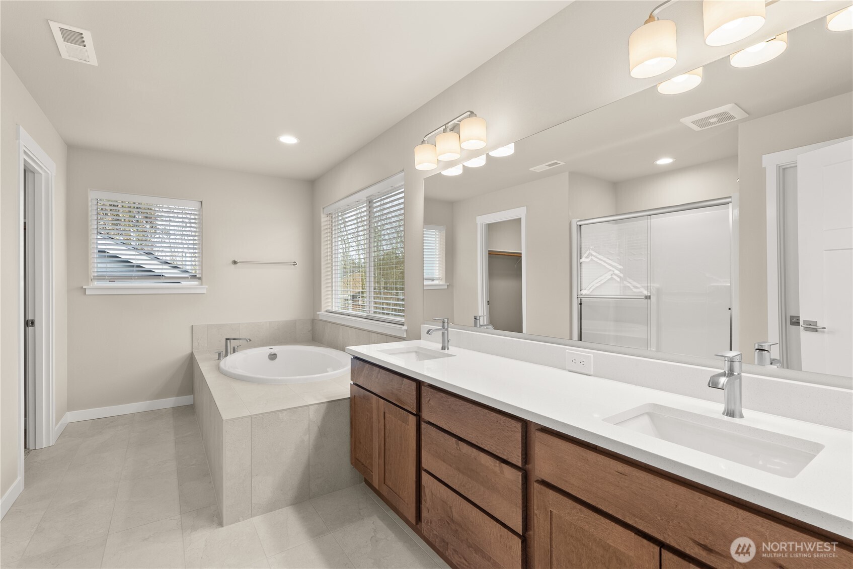 7308 Jenner Street Southwest Tumwater, WA 98512 - Photo 19 of 34 a spacious bathroom with a double vanity sink a large mirror and a bathtub