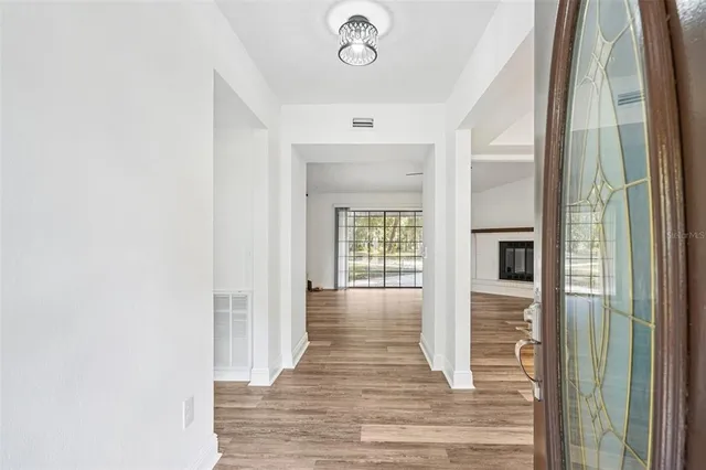 a view of an empty room with a window and wooden floor