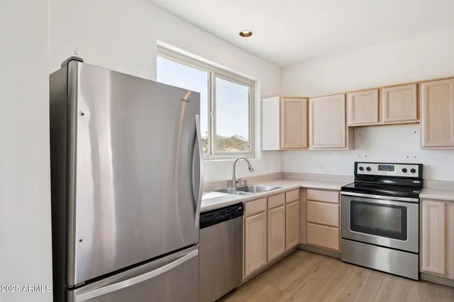 a kitchen with stainless steel appliances a sink a stove a refrigerator and cabinets