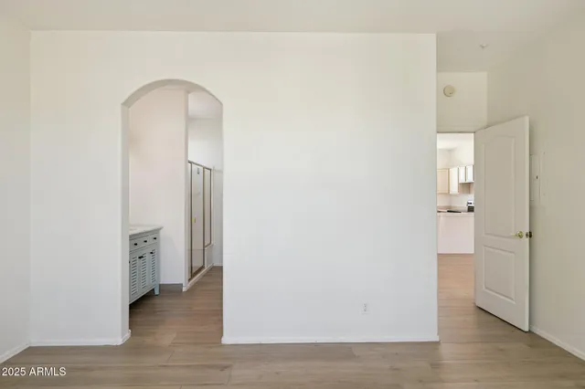 an empty room with wooden floor chandelier fan and windows