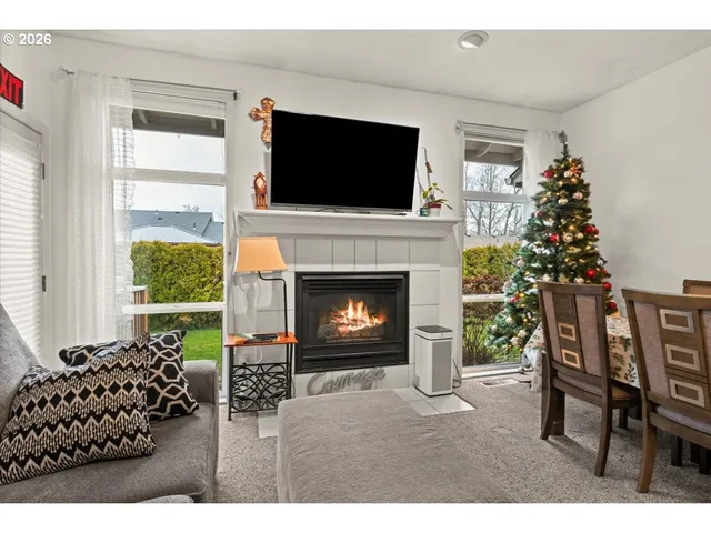 a living room with a fireplace a flat screen tv and a large window