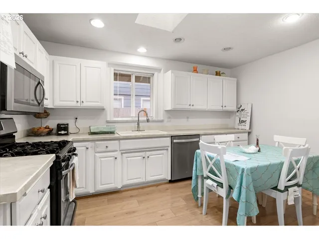 a kitchen with stainless steel appliances granite countertop a table chairs sink and cabinets