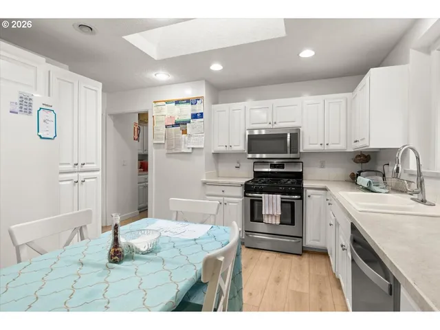 a kitchen with stainless steel appliances granite countertop a stove top oven a sink and a refrigerator