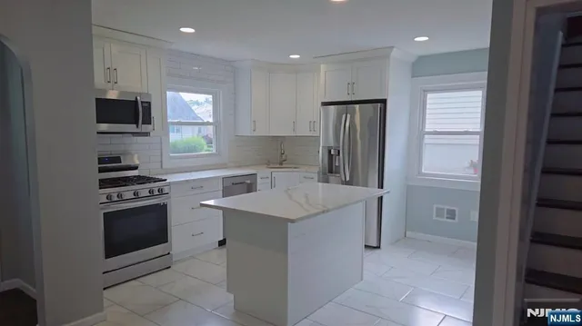 a kitchen with stainless steel appliances granite countertop a refrigerator and a stove top oven