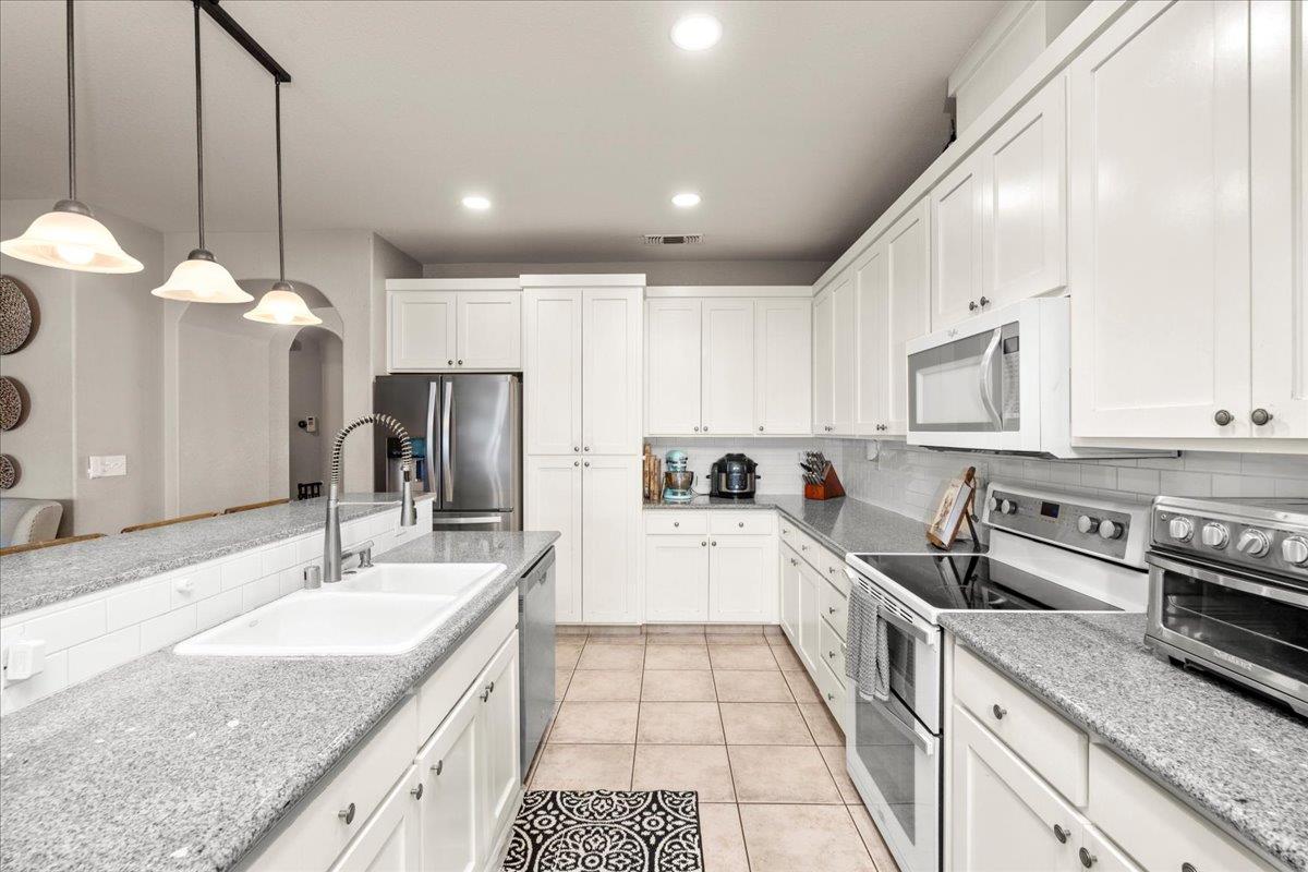 1725 Stonum Road Modesto, CA 95351 - Photo 11 of 34 a open kitchen with stainless steel appliances granite countertop a sink and a stove