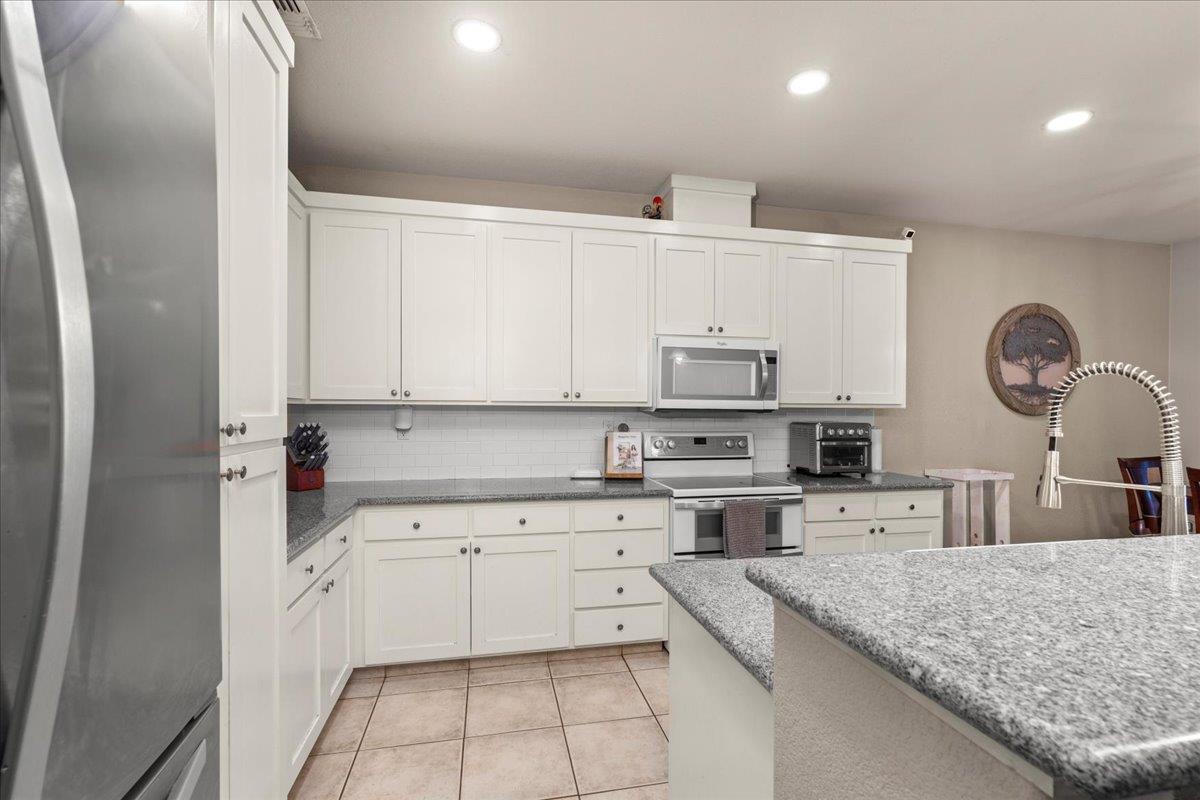 1725 Stonum Road Modesto, CA 95351 - Photo 13 of 34 a kitchen with a sink dishwasher and white cabinets with wooden floor