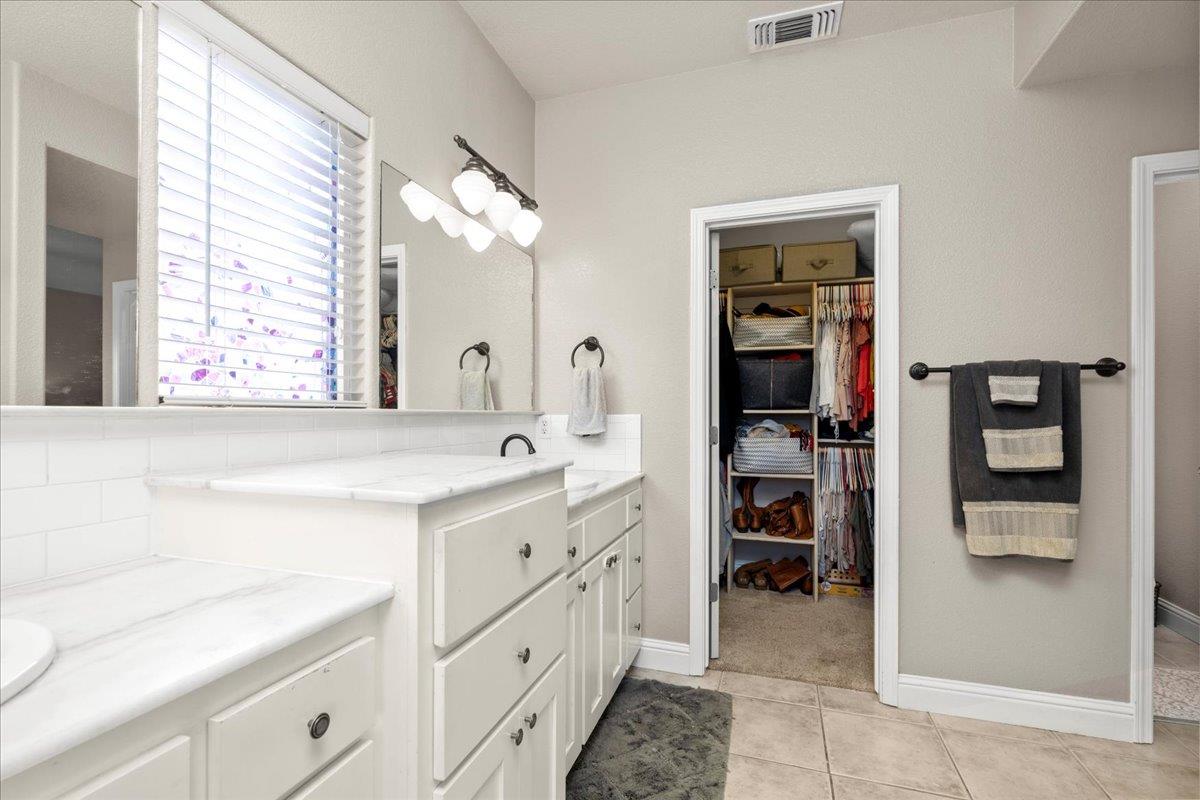 1725 Stonum Road Modesto, CA 95351 - Photo 16 of 34 a spacious bathroom with a double vanity sink a large mirror and a bathtub