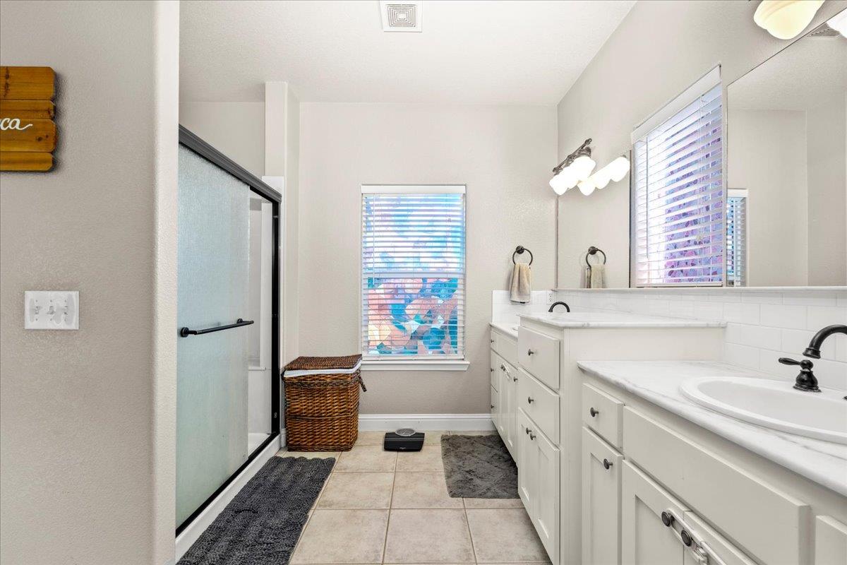 1725 Stonum Road Modesto, CA 95351 - Photo 17 of 34 a spacious bathroom with a double vanity sink a mirror a bathtub and a shower