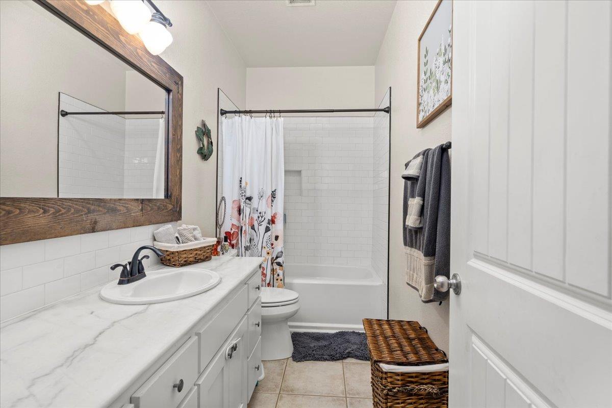 1725 Stonum Road Modesto, CA 95351 - Photo 22 of 34 a bathroom with a granite countertop sink a mirror a bathtub and shower