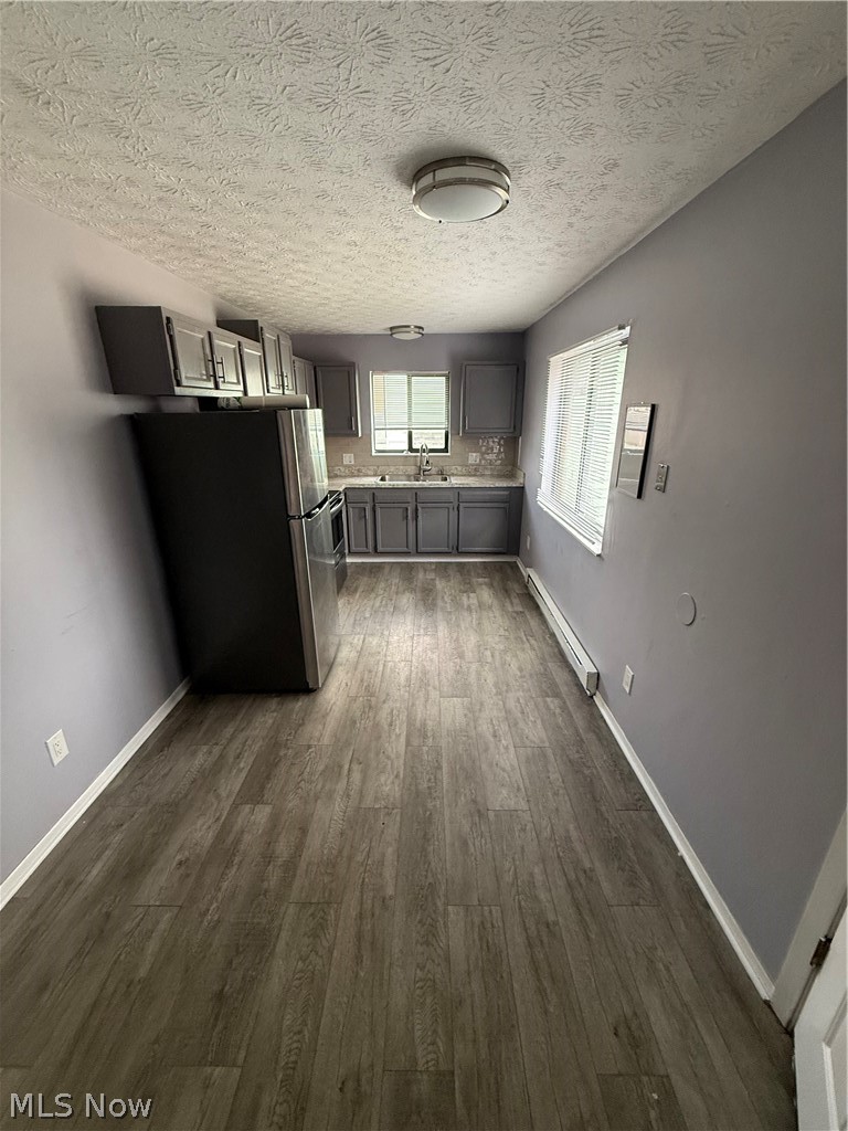 662 Sumner Street Akron, OH 44311 - Photo 3 of 10 Kitchen with gray cabinetry, fridge, light countertops, a baseboard heating unit, and dark wood-style floors