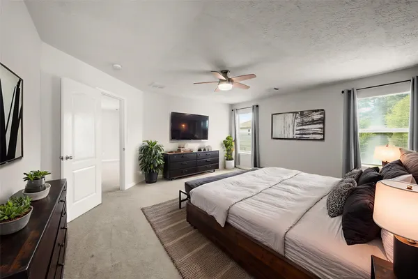a bedroom with a bed a chandelier and a flat screen television