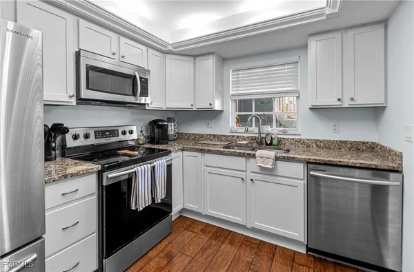 a kitchen with granite countertop white cabinets and stainless steel appliances