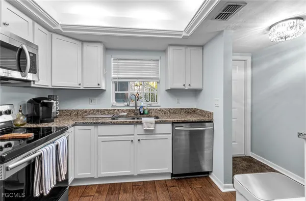 a kitchen with stainless steel appliances granite countertop a stove a sink and a microwave