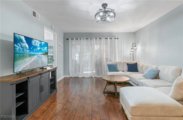 a living room with furniture a flat screen tv and wooden floor