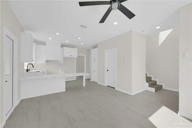 a large white kitchen with a sink stainless steel appliances and cabinets