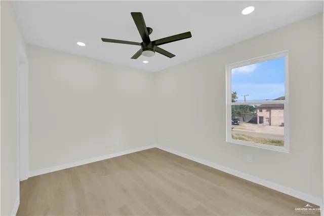 a view of a big room with wooden floor a ceiling fan and windows