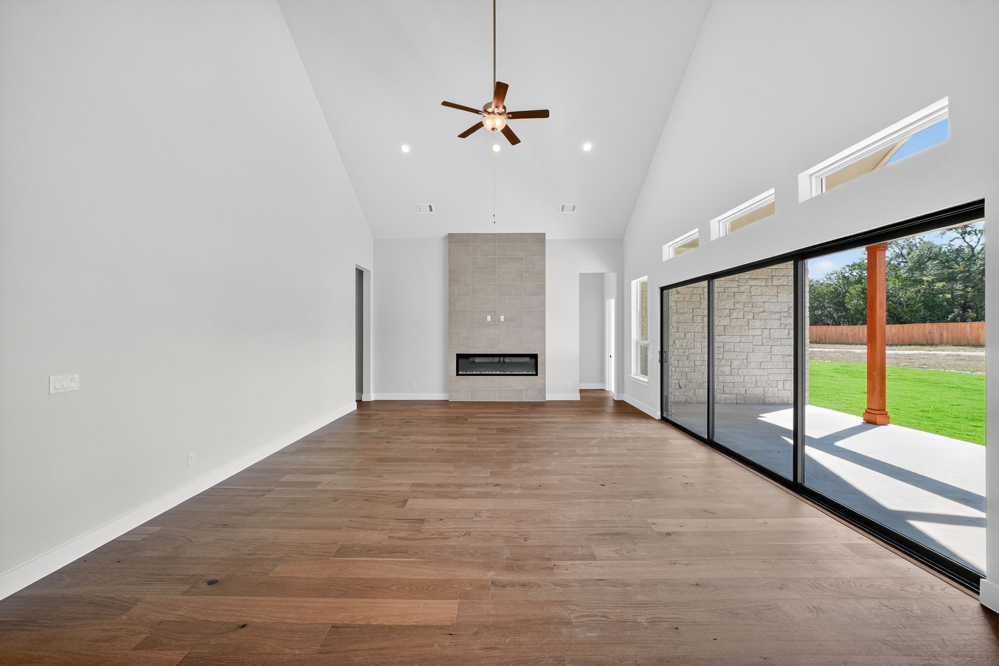 205 Three Rivers Road Georgetown, TX 78633 - Photo 5 of 32 Unfurnished living room featuring high vaulted ceiling, a tile fireplace, light wood-style flooring, ceiling fan, and recessed lighting