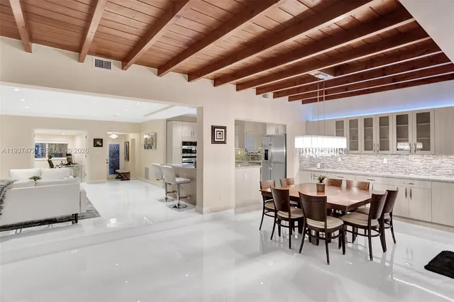 a dining hall with stainless steel appliances granite countertop a table chairs and a refrigerator