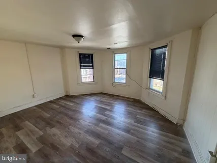 a view of empty room with window and wooden floor