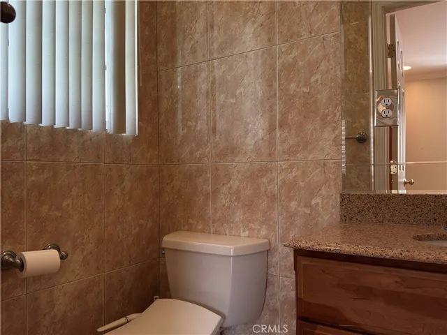 a bathroom with a granite countertop toilet and a sink