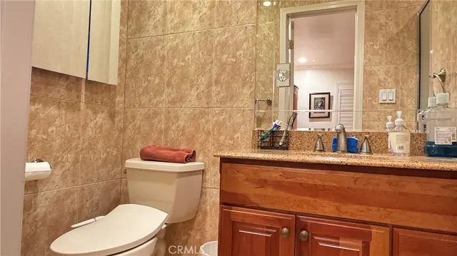a bathroom with a granite countertop toilet sink and mirror