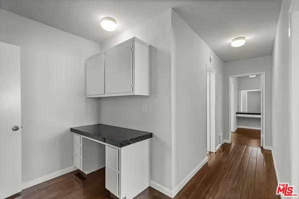 a kitchen with wooden floor and electronic appliances
