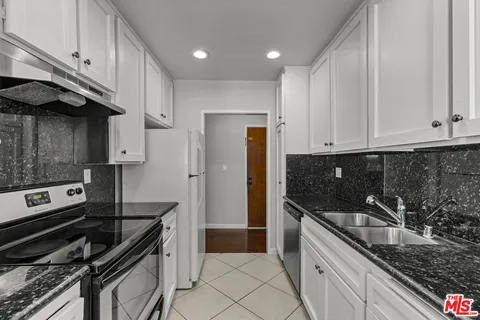 a kitchen with granite countertop a stove sink and cabinets