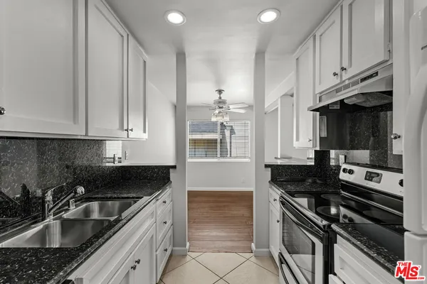 a kitchen with granite countertop a sink stove and cabinets