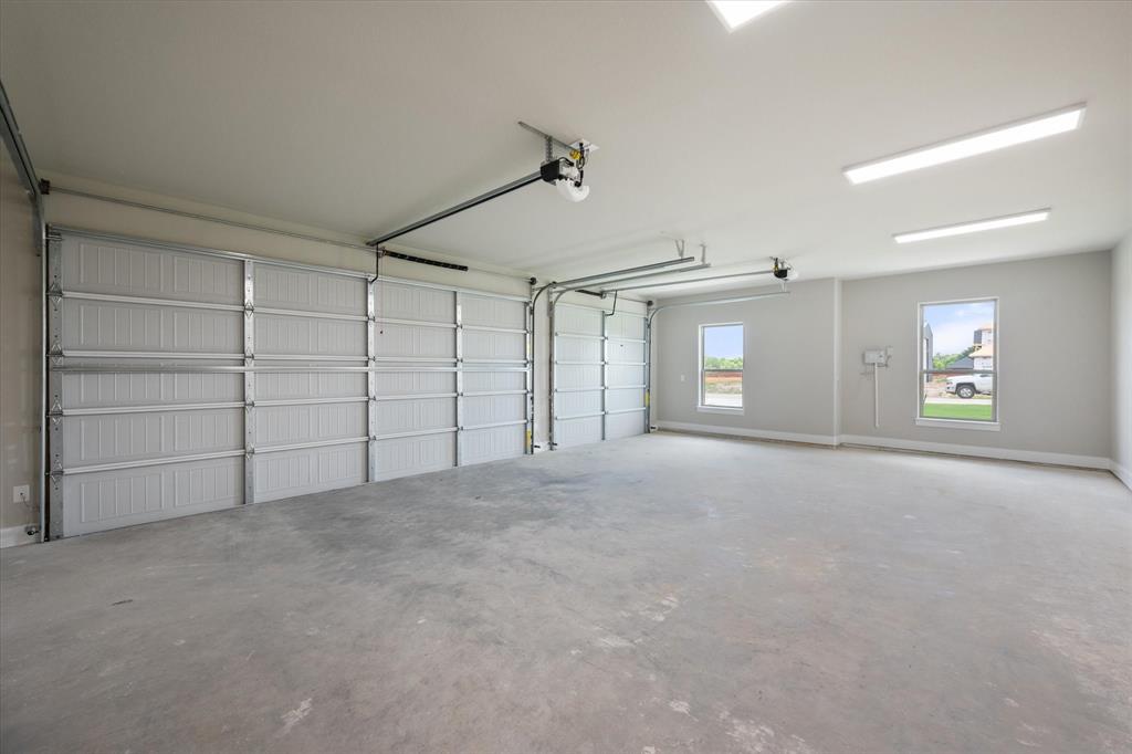 6610 Waggoner Way Midlothian, TX 76065 - Photo 29 of 40 Spacious 3-car garage featuring two overhead doors, concrete flooring, overhead fluorescent lighting, and two windows providing exterior visibility