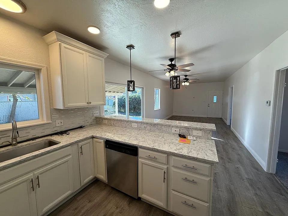 150 North Acacia Avenue Ripon, CA 95366 - Photo 31 of 54 a kitchen with a sink dishwasher a stove and white cabinets with wooden floor