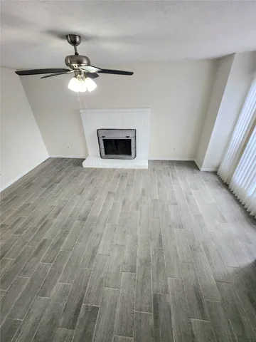 a view of an empty room with wooden floor and a chandelier fan
