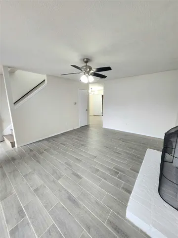 an empty room with wooden floor and a ceiling fan