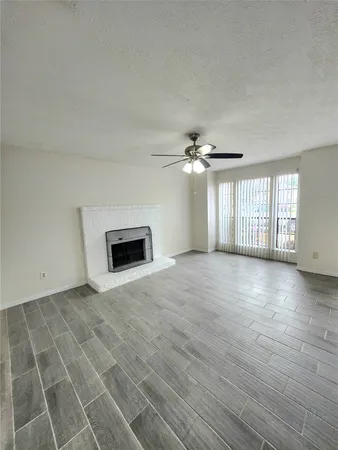 an empty room with windows and fireplace