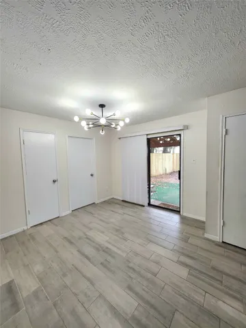 an empty room with wooden floor hallway and windows