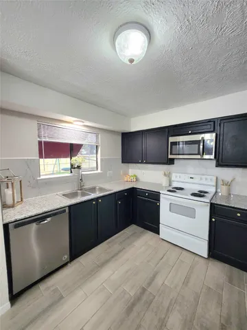 a large kitchen with stainless steel appliances granite countertop a stove sink and cabinets
