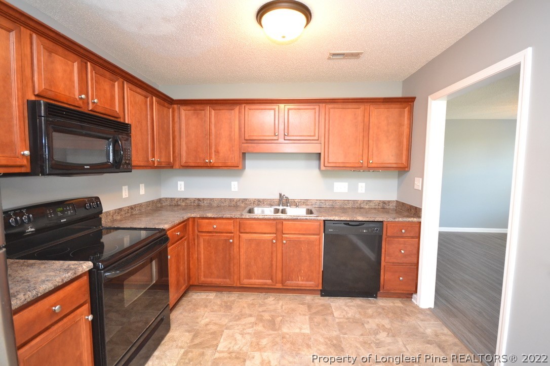 2330 Chasewater Road Fayetteville, NC 28306 - Photo 12 of 44 a kitchen with granite countertop a stove top oven microwave and cabinets