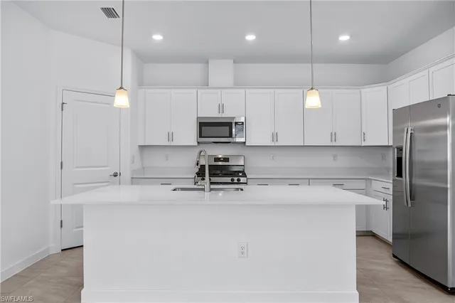 a kitchen with kitchen island a sink stainless steel appliances and cabinets