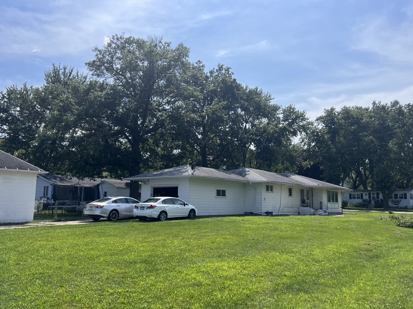 a backyard of a house with table and chairs plants and large tree