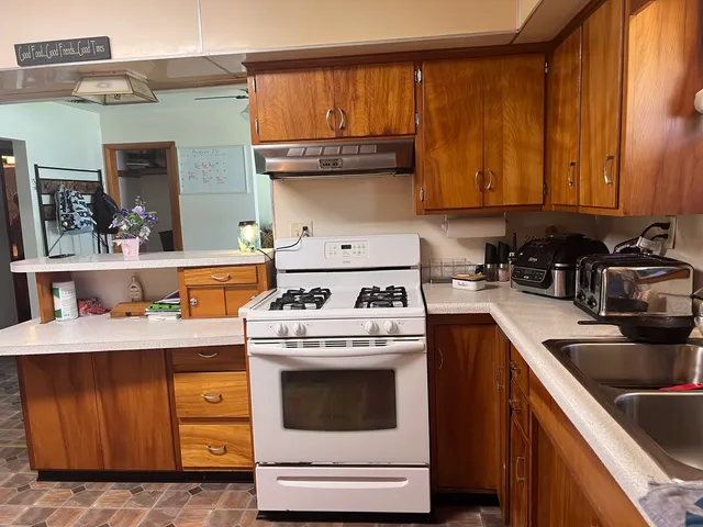 a kitchen with granite countertop a sink a stove and cabinets